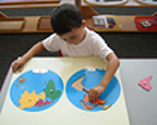 Little boy playing on the table with a map puzzle